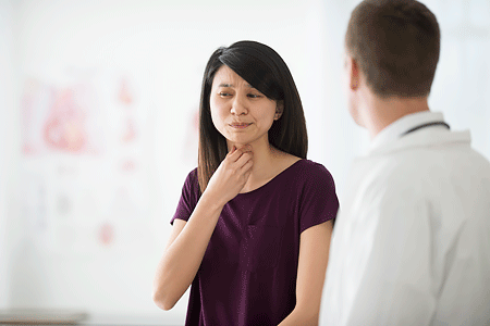 A women telling her doctor about her sore throat during doctor's appointment.