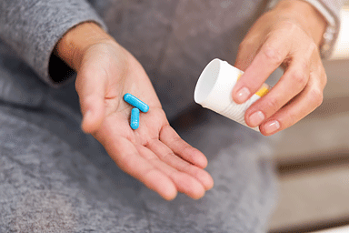 Hands of woman holding prescription medicine bottle and pills