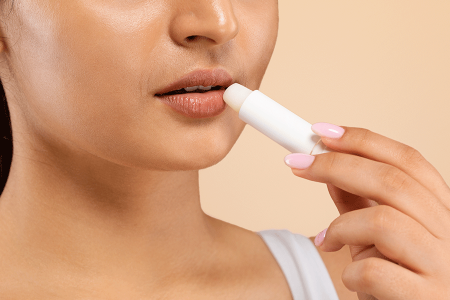 Woman applying lip balm with SPF 30 to prevent a cold sore