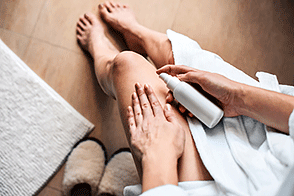 Woman applying lotion to legs