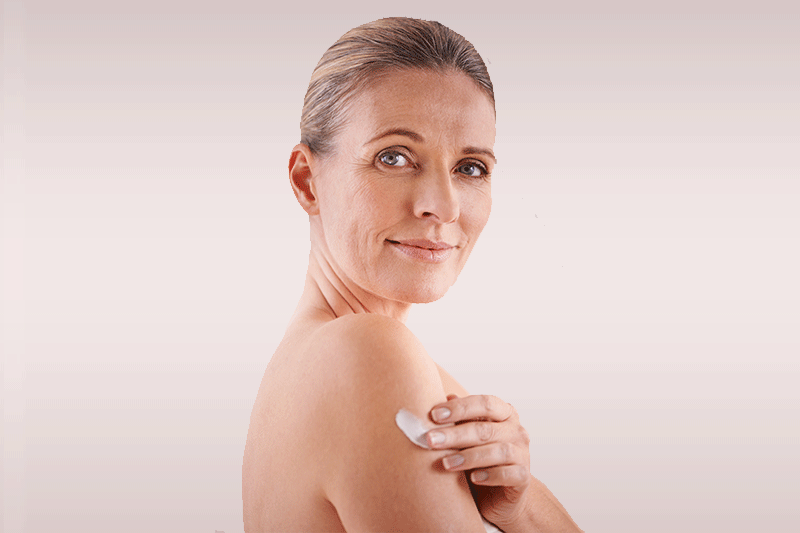 Woman applying moisturizer to her upper arm