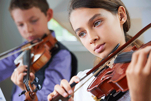 Two young children playing violin.