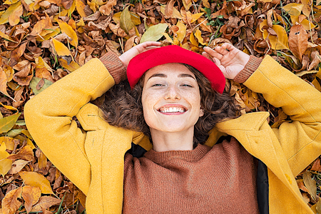 Smiling woman lying on autumn leaves