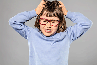Irritated young girl scratching head due to head lice
