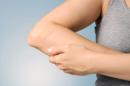 Female arm with adhesive bandage on blue background