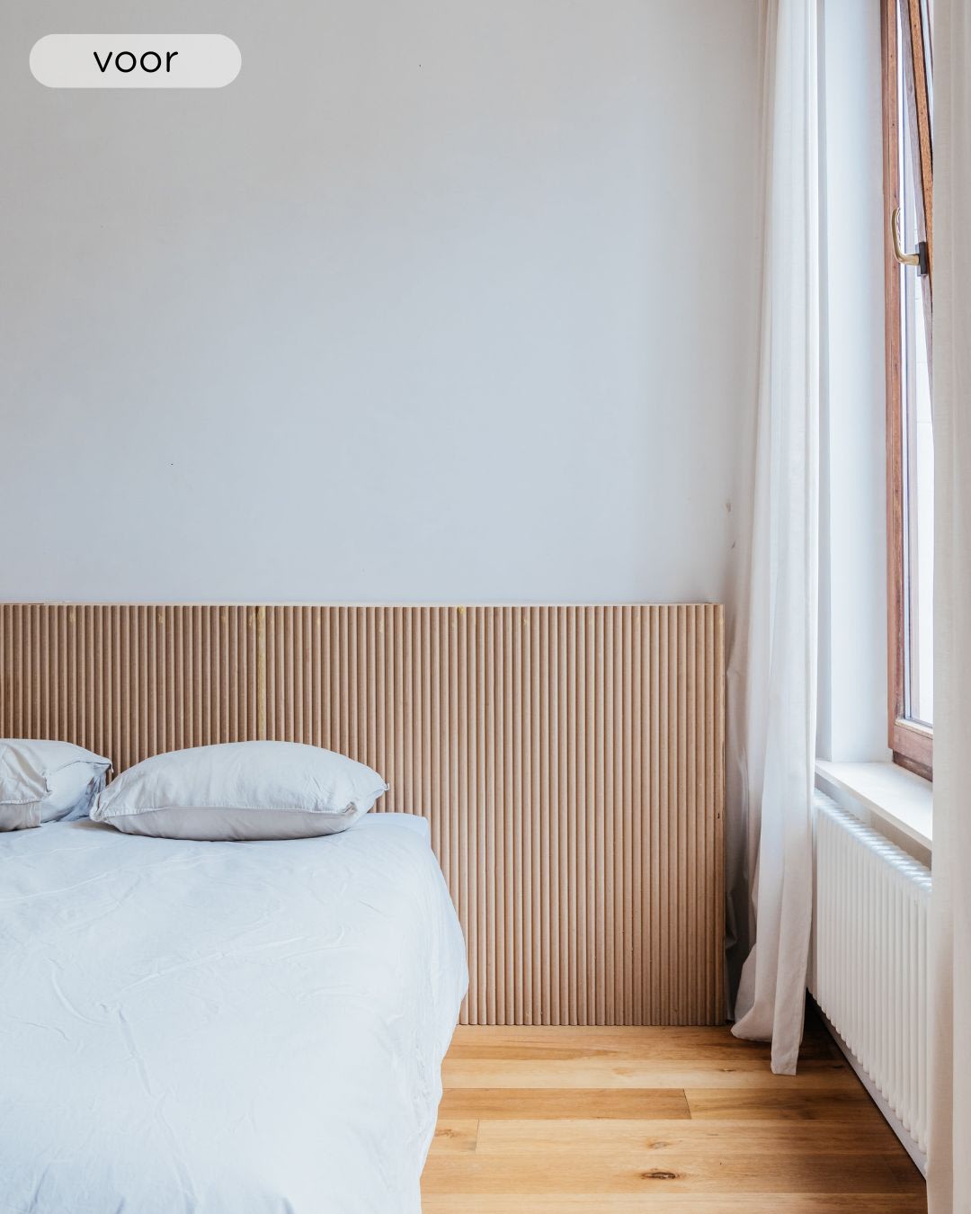 een slaapkamer met witte muren, houten vloer en donkerhouten deur en achterwand. Het bed heeft een wit dekbedovertrek en de lampenkap is rond en wit.