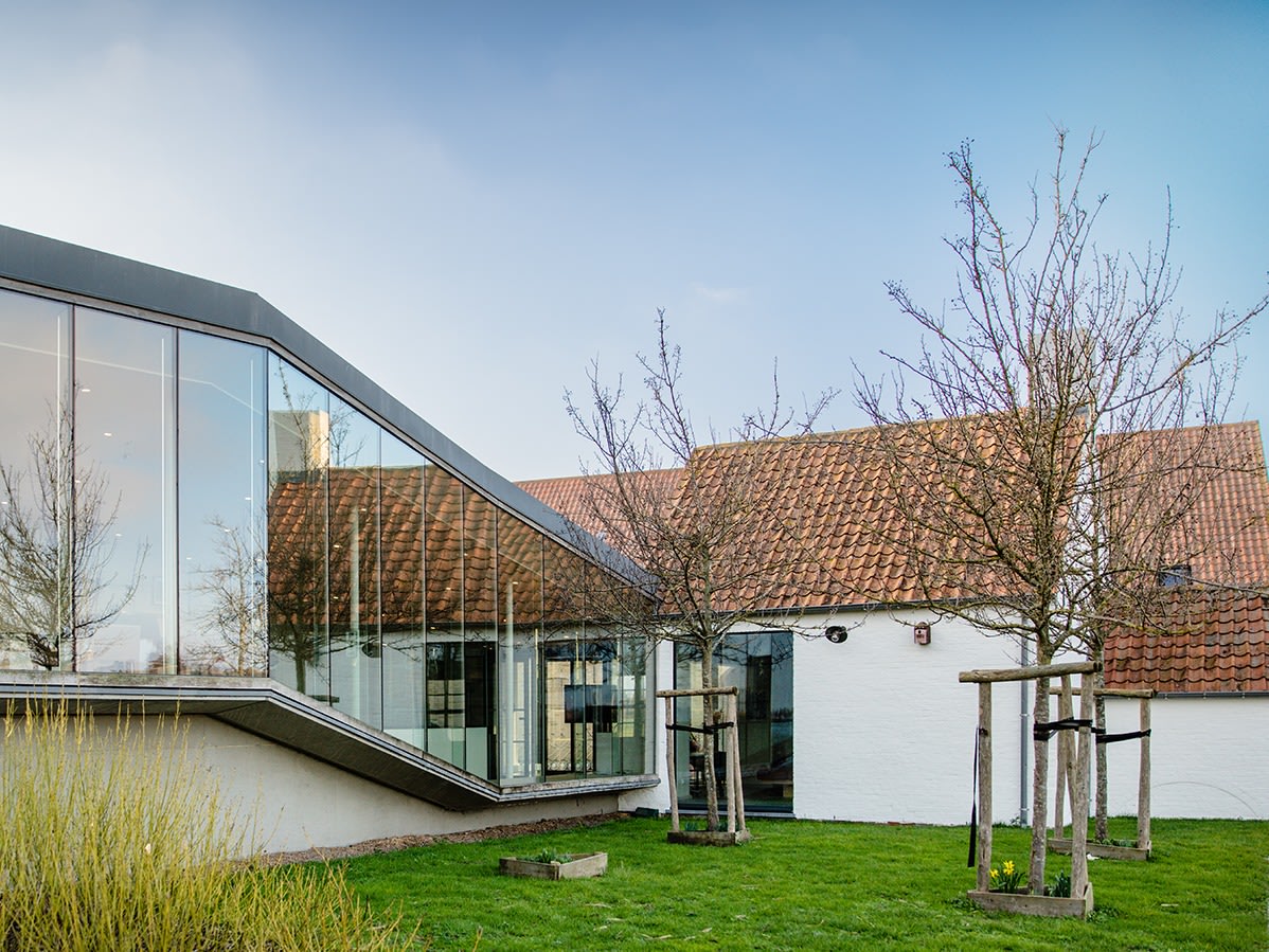witte hoeve met rood dak en glaswand