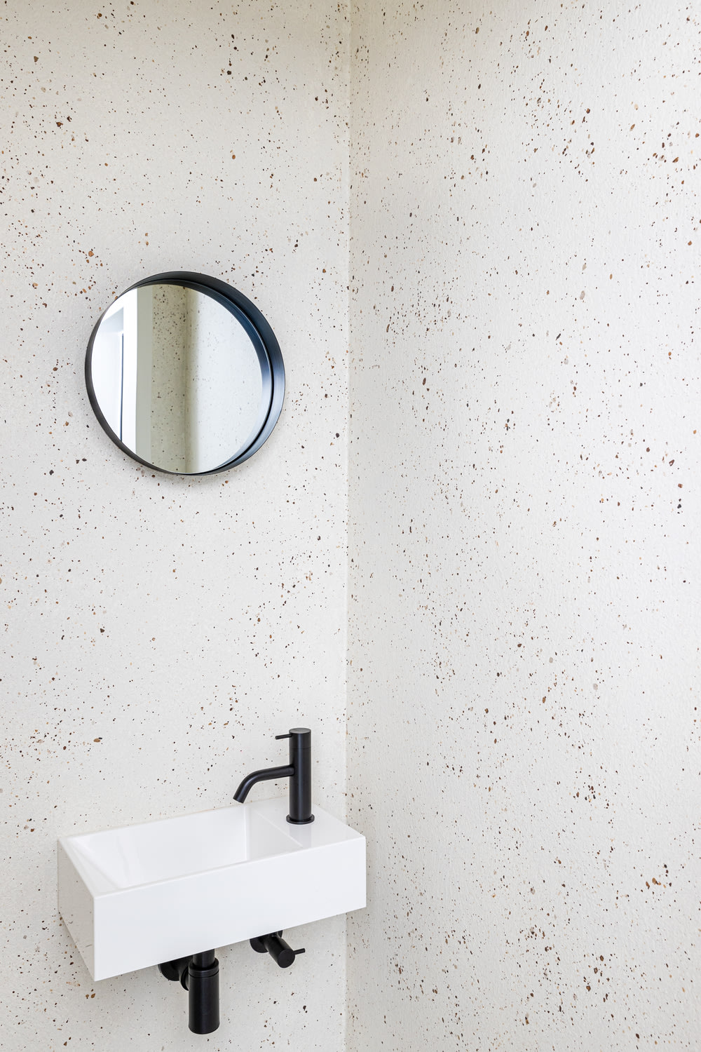 Inspiratiebeeld colora - Stone Art terrazzo in het toilet - witte wasbak en ronde spiegel - colora magazine herfst 2022