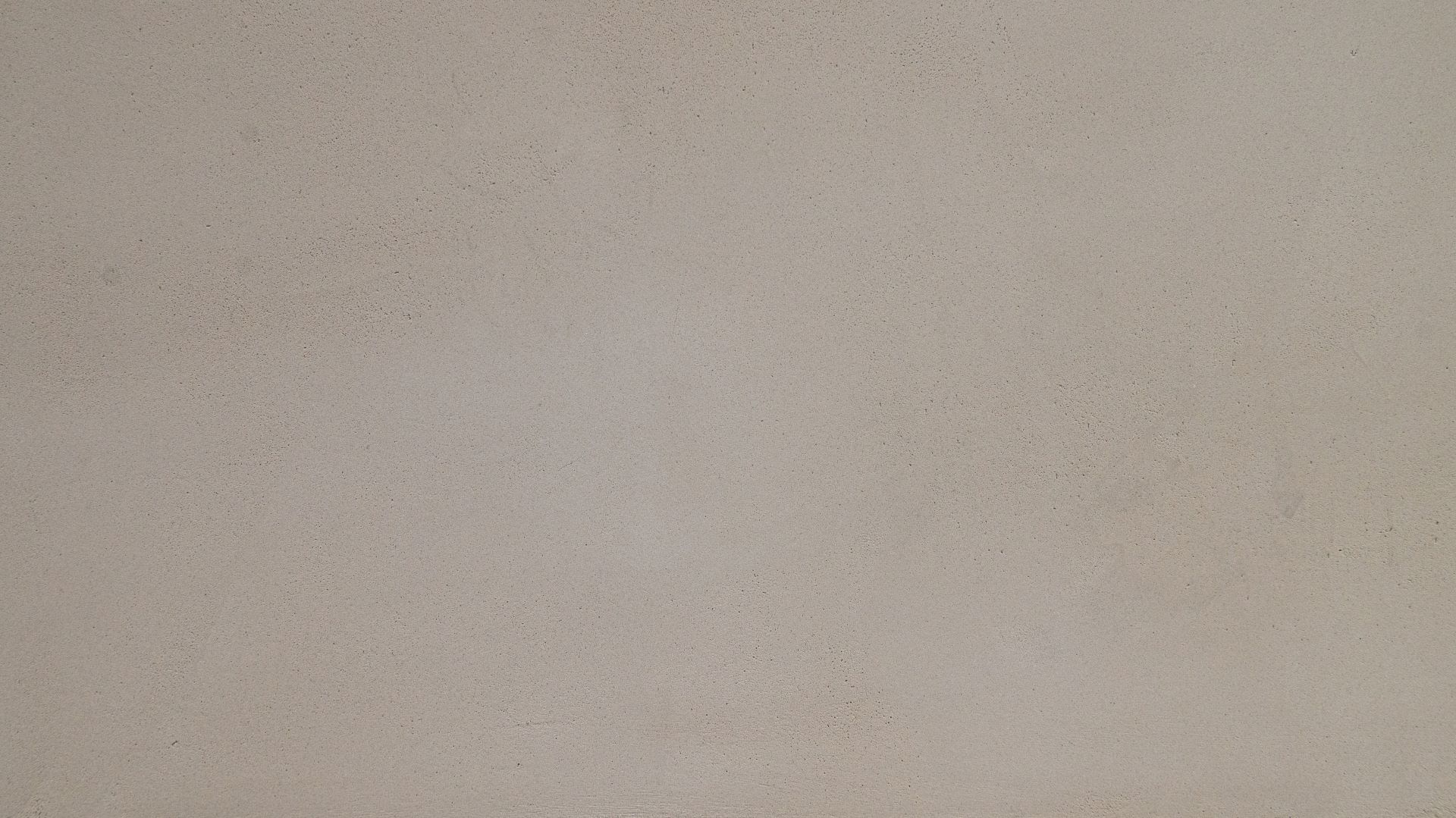 Een effen, lichtbeige muur met een gladde textuur en lichte kleurvariaties.