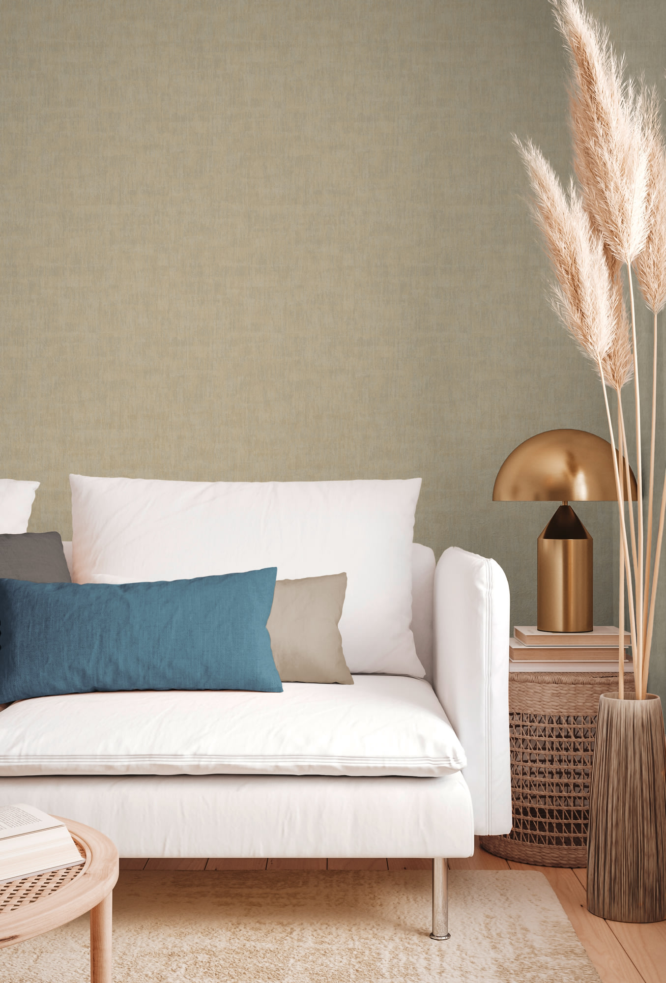 Een witte sofa met blauwe en beige kussens staat naast een stapel boeken en een ronde lamp, met pampagras in een vaas op een geweven bijzettafel. Neutrale tinten domineren de inrichting.