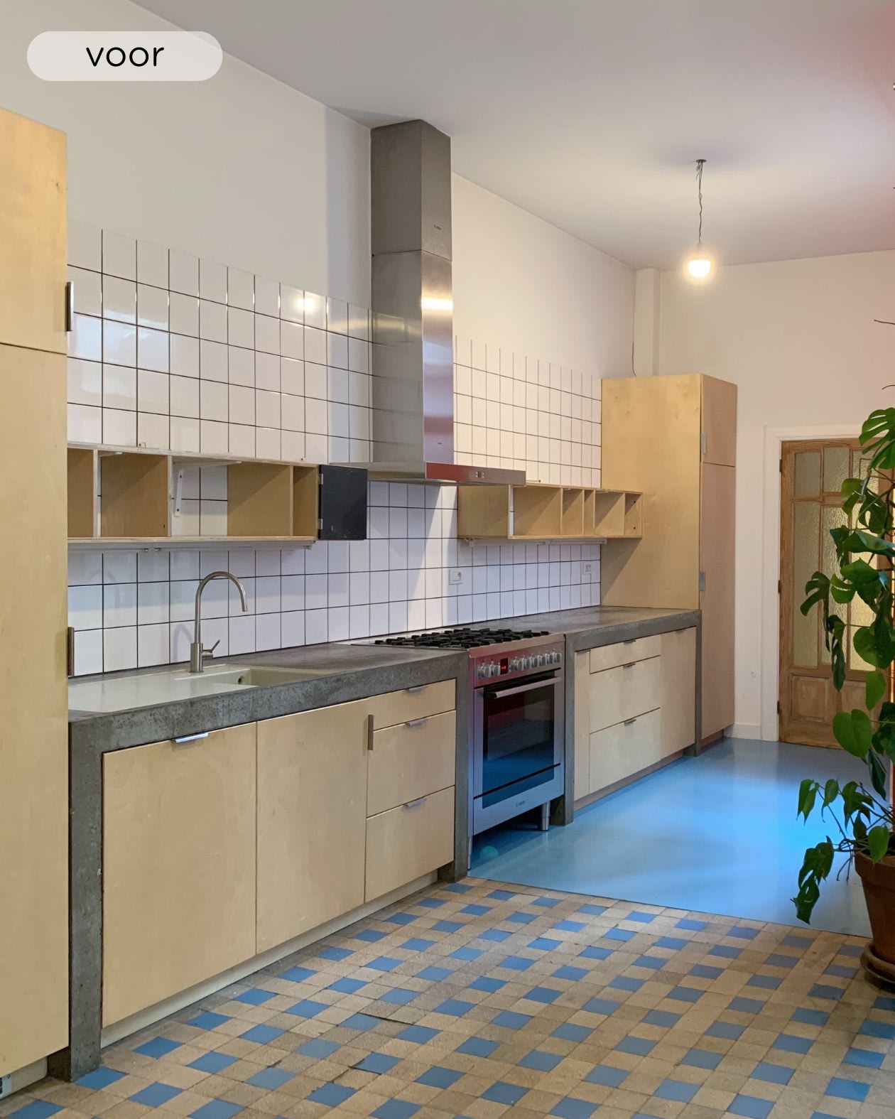 Keuken met houten keukenkasten, een betonnen werkblad en dampkamp in inox. De vloer bestaat uit vierkante tegels en beton alsook de spatwand heeft witte tegeltjes
