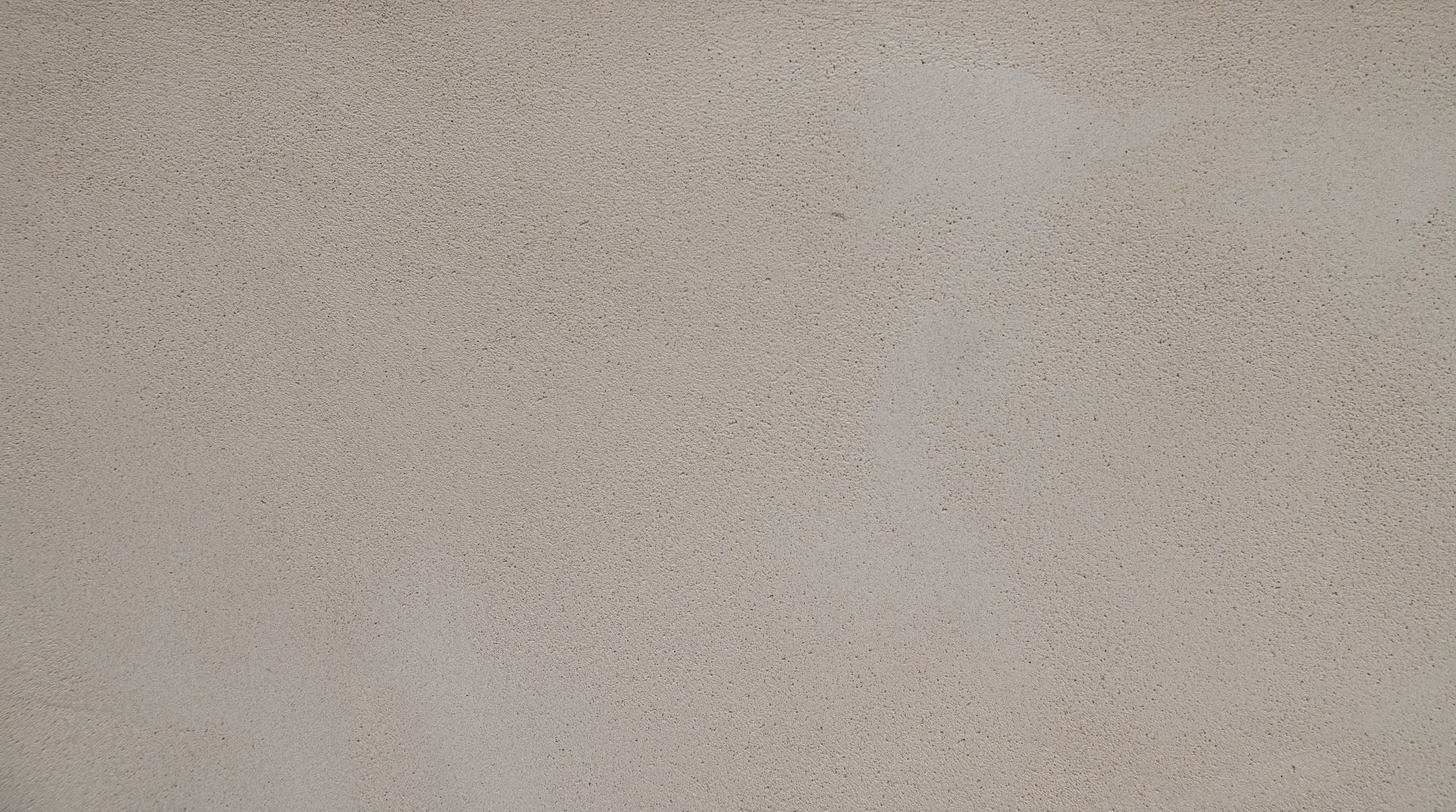 Een close-up van een effen, beige structuurmuur met subtiele variaties in kleur en oppervlaktepatroon.