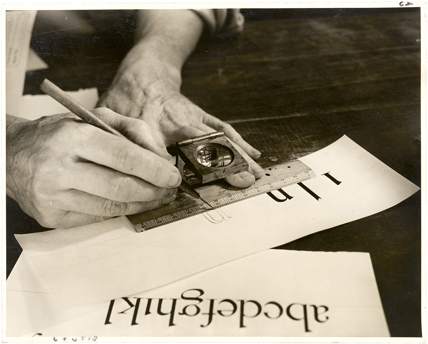 Dwiggins drawing letters using a loupe and a ruler