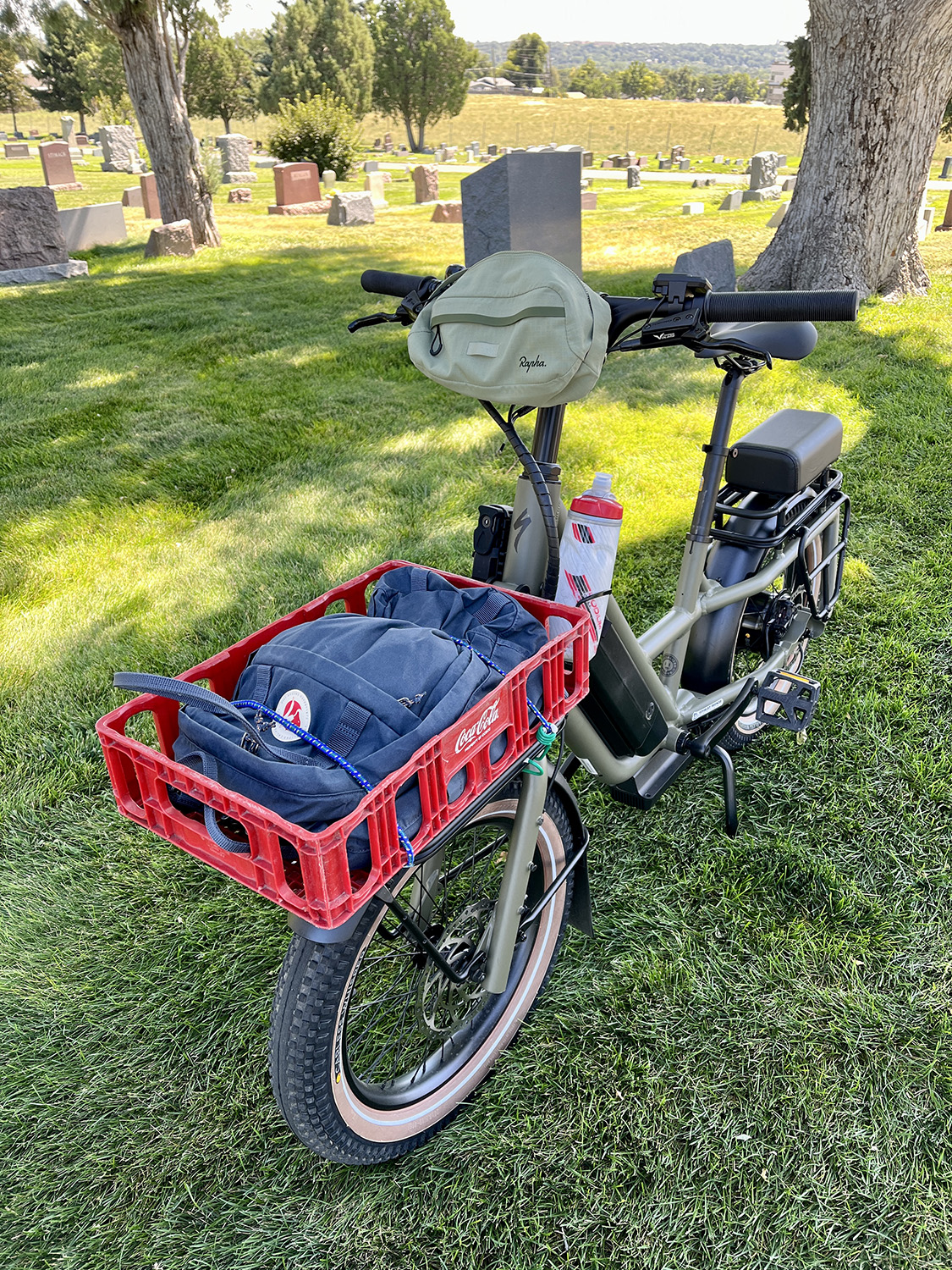 Globe Haul ST bike with a red crate and blue laptop bag in a cemetery