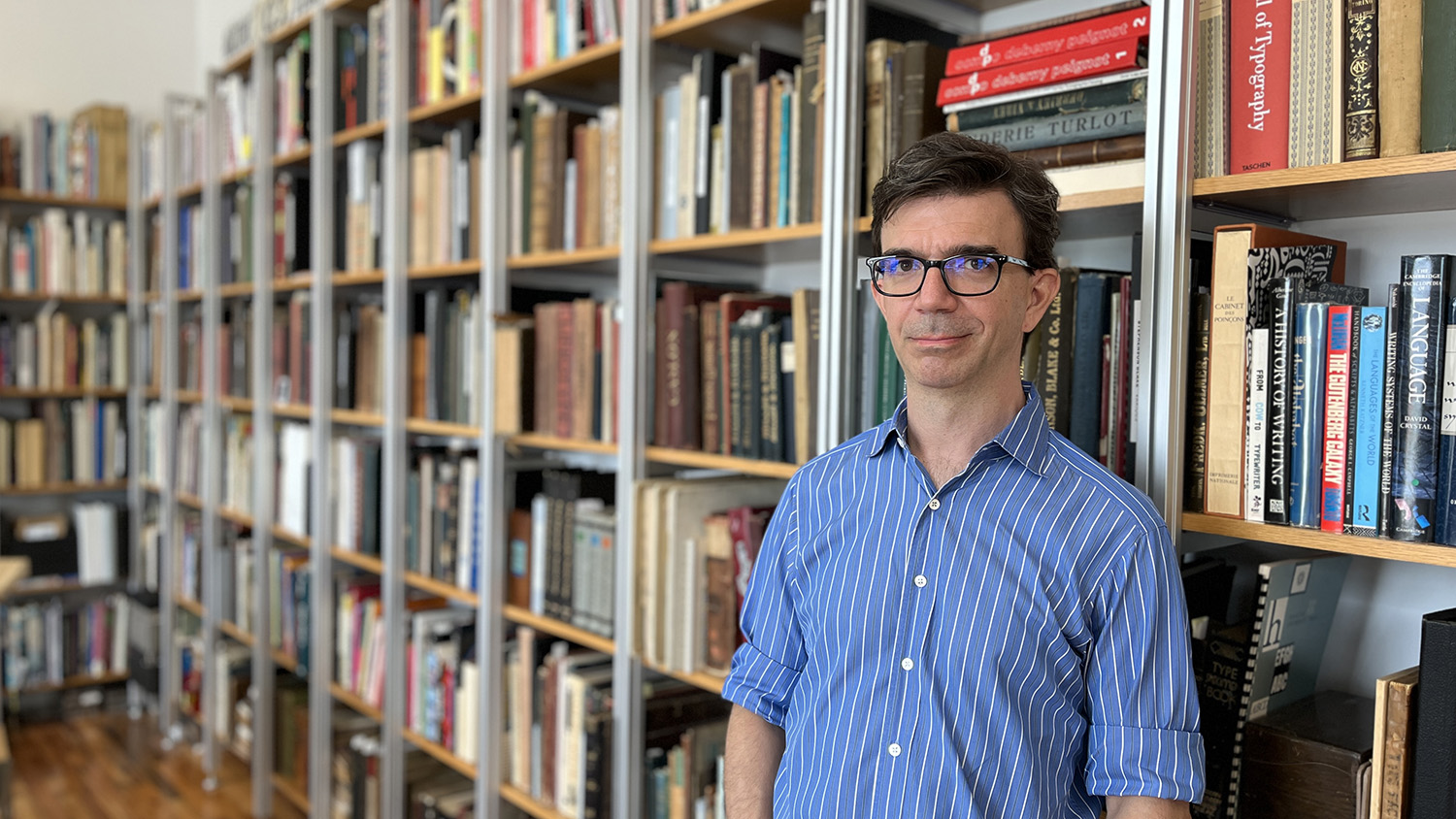 Tobias Frere-Jones standing in front of his impressive typographic library in Brooklyn, NY