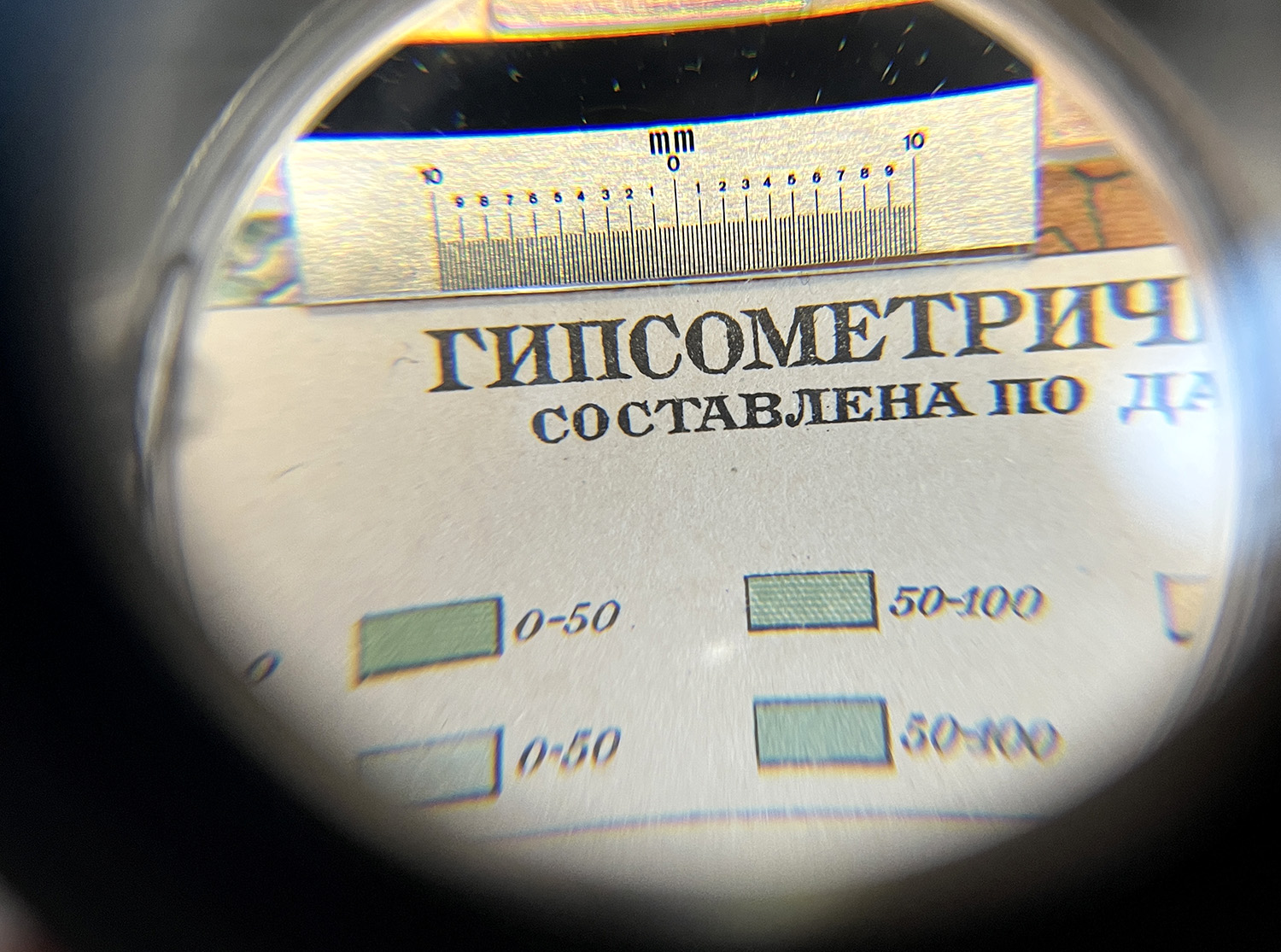 Looking through a loupe at Cyrillic lettering in an atlas