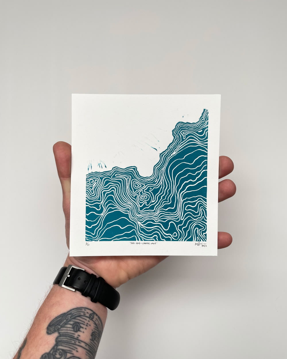A hand holding a square-shaped blue and white print