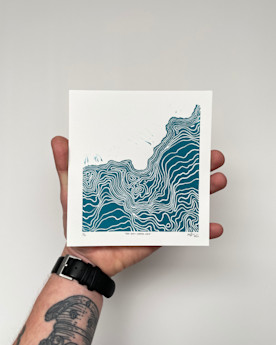 A hand holding a square-shaped blue and white print