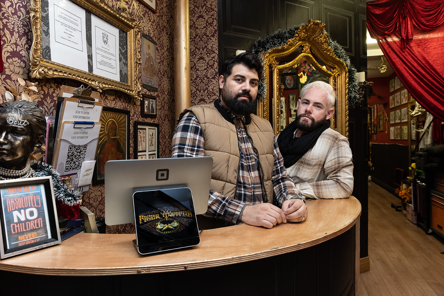 Danny McGuinness and Nelson Guerra of Tiger Tattoo sitting on a sofa inside their shop
