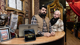 Danny McGuinness and Nelson Guerra of Tiger Tattoo sitting on a sofa inside their shop