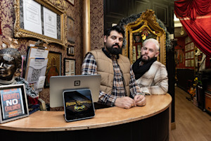 Danny McGuinness and Nelson Guerra of Tiger Tattoo sitting on a sofa inside their shop