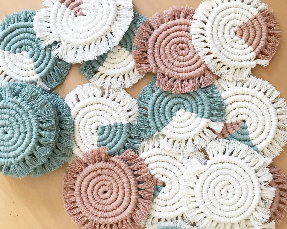 an assortment of woven spiral coasters in white, teal, and blush tones