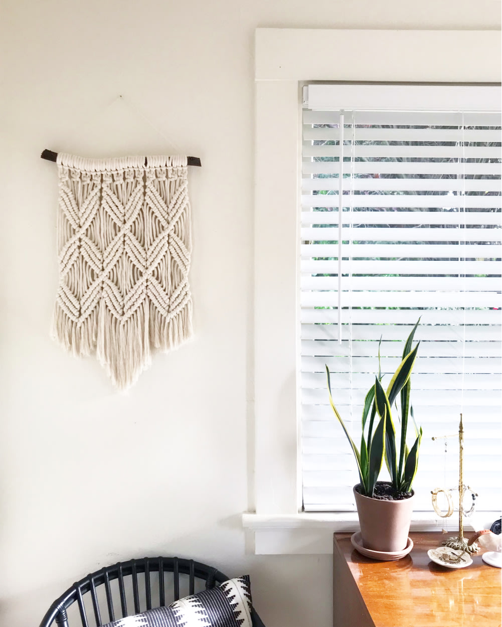 A macrame wall hanging next to a window