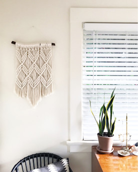 A macrame wall hanging next to a window