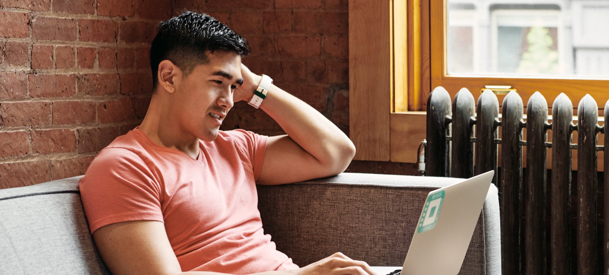 photo showing a person sitting on a couch and using a laptop