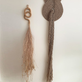 two earth tone decorative wall hangings on a white wall