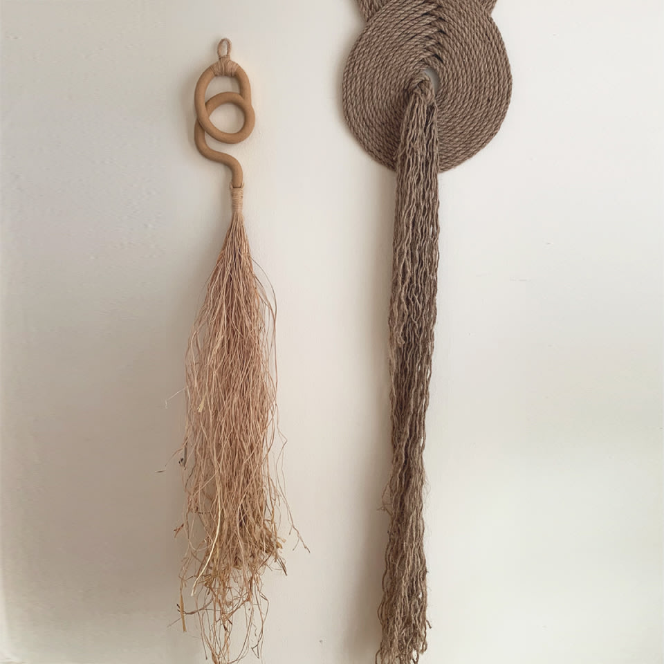 two earth tone decorative wall hangings on a white wall