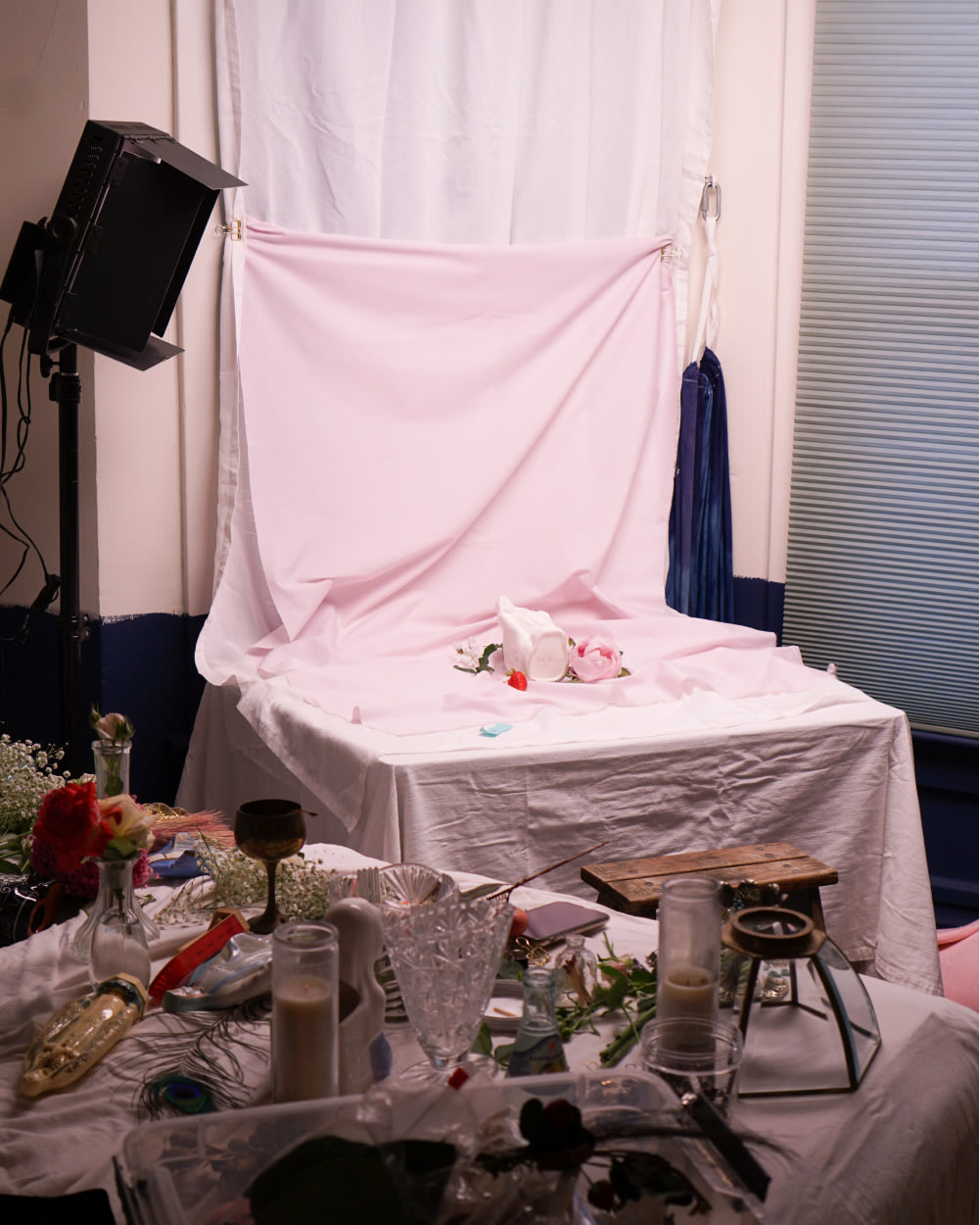 A photoshoot setup with assorted objects in the foreground: candles, glasses, flowers and more