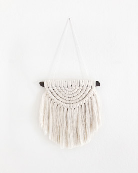 a macrame wall decoration on a white wall