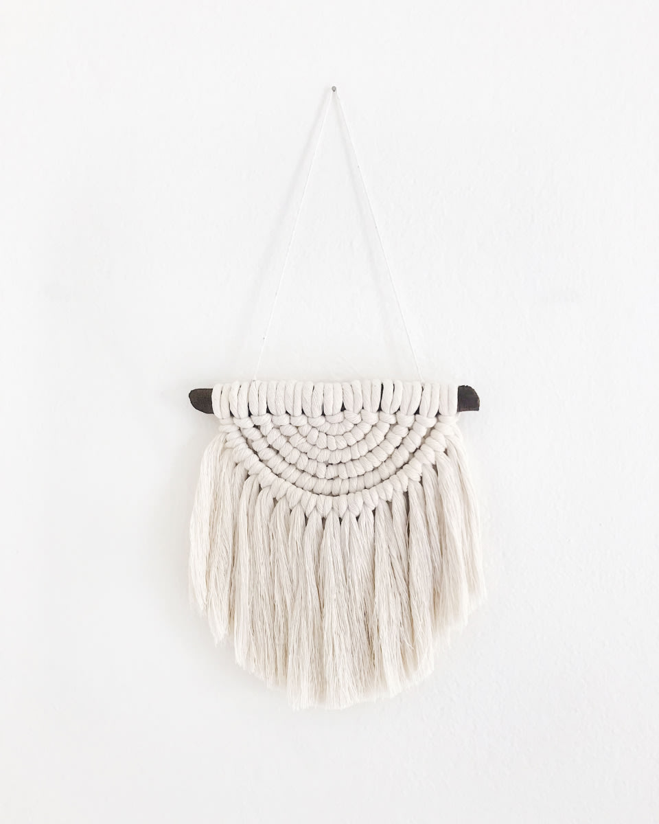 a macrame wall decoration on a white wall