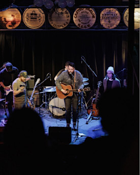 Ben plays the guitar on stage with a band