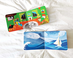 two illustrated childrens’ books lay open on white linens
