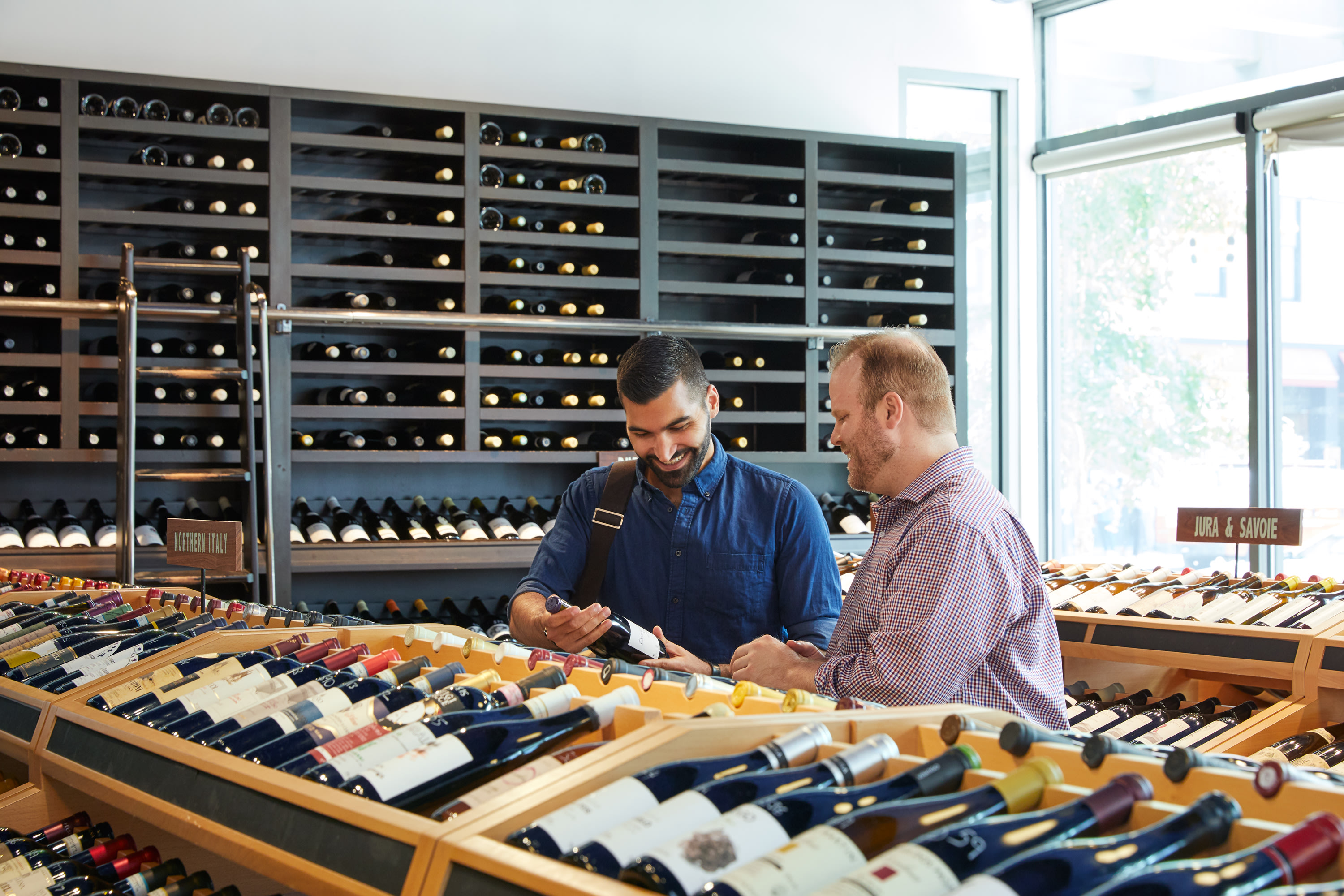two men looking at a wine bottle