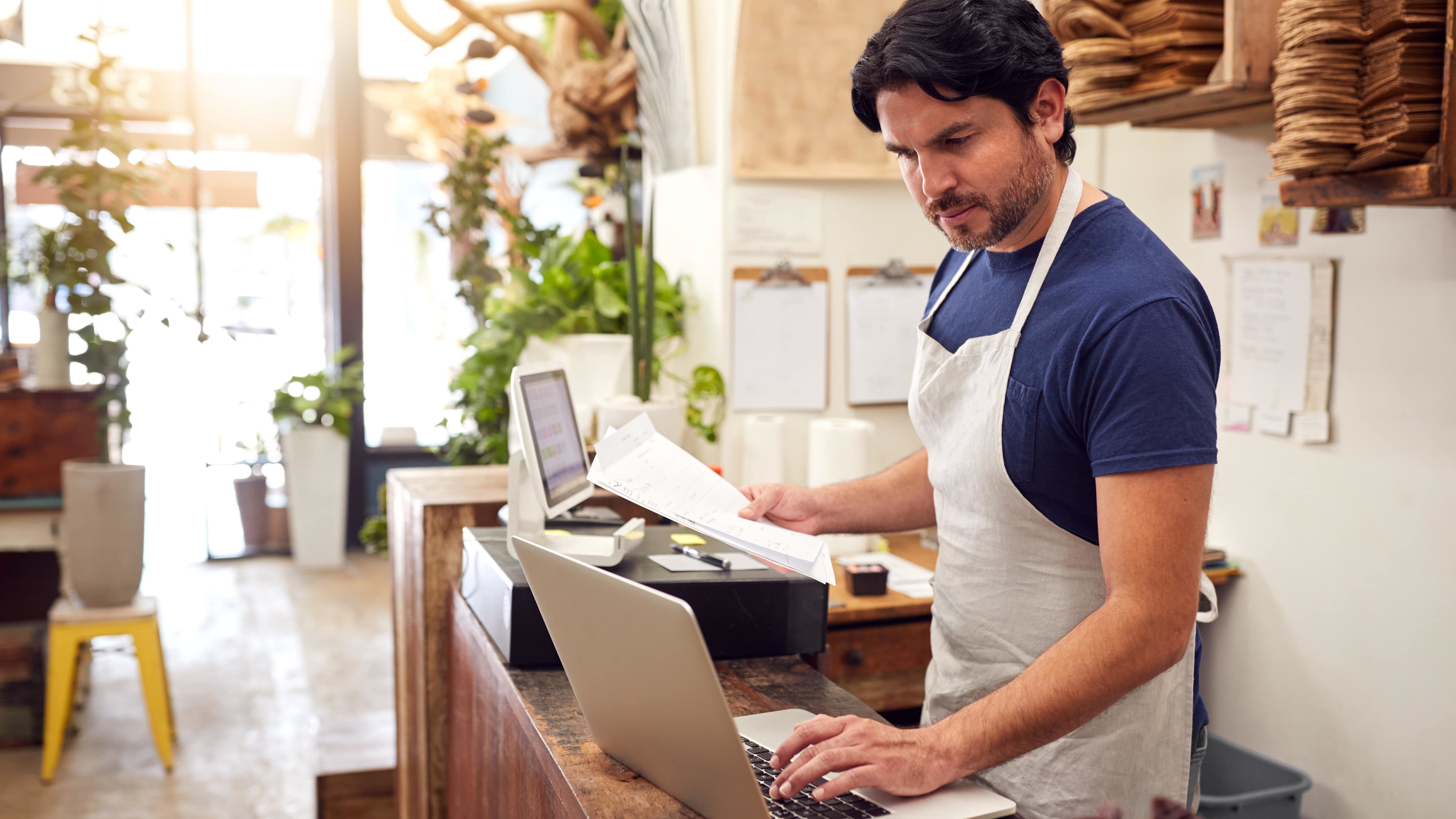 A florist working from a laptop at their front desk