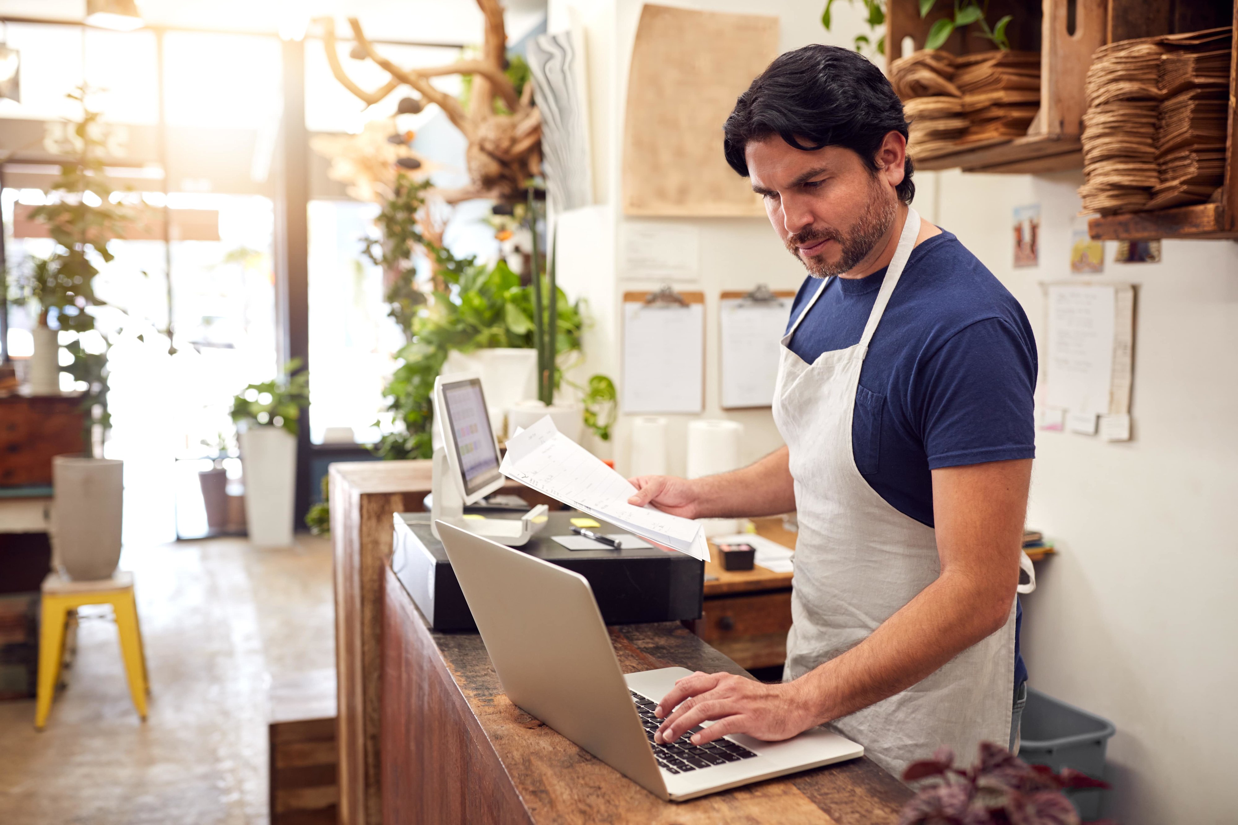 A florist working from a laptop at their front desk