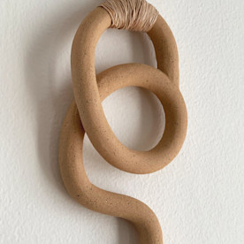 an earth tone decorative wall hanging on a white wall