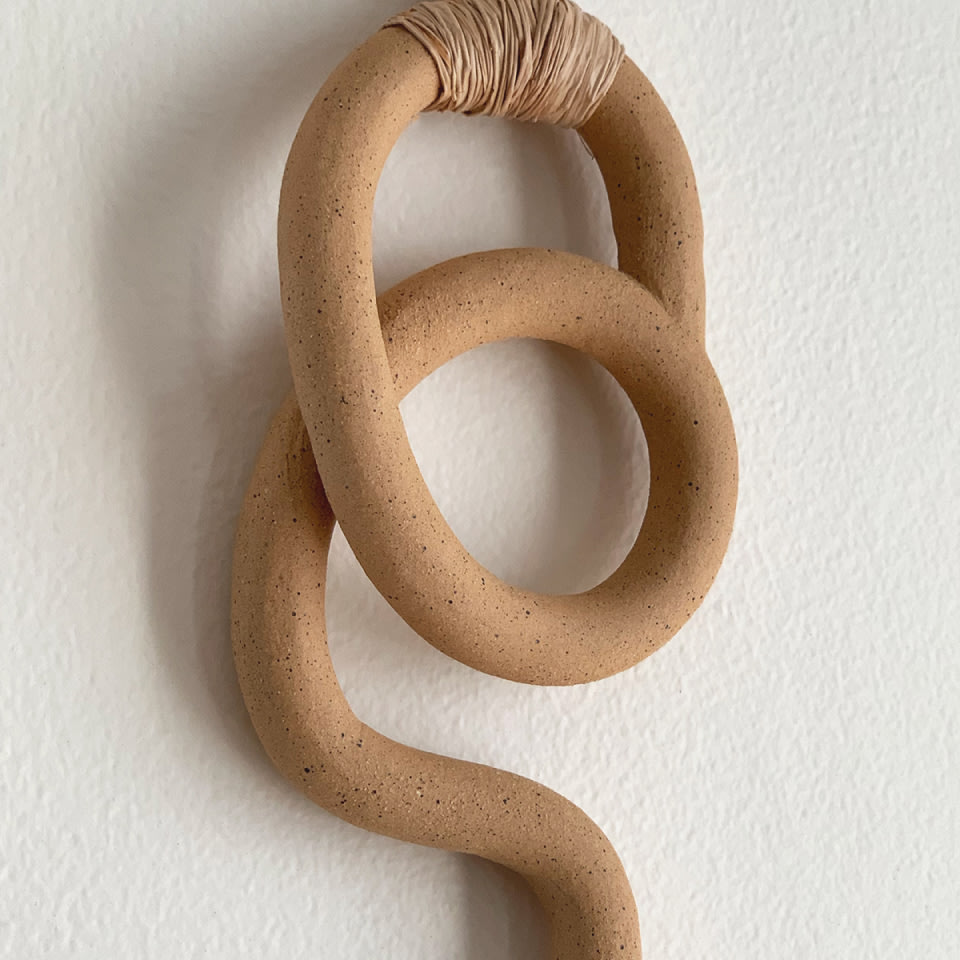an earth tone decorative wall hanging on a white wall