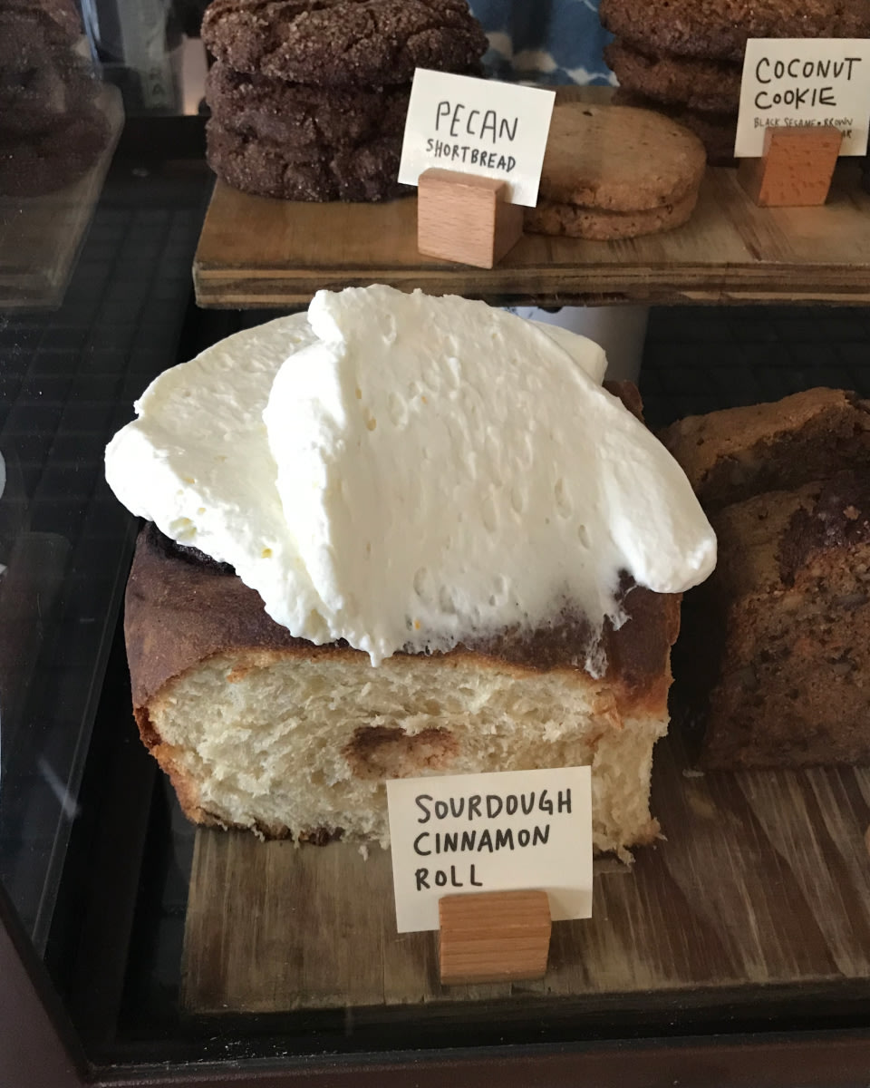 a photo of baked goods with a large sourdough cinnamon roll in the foreground