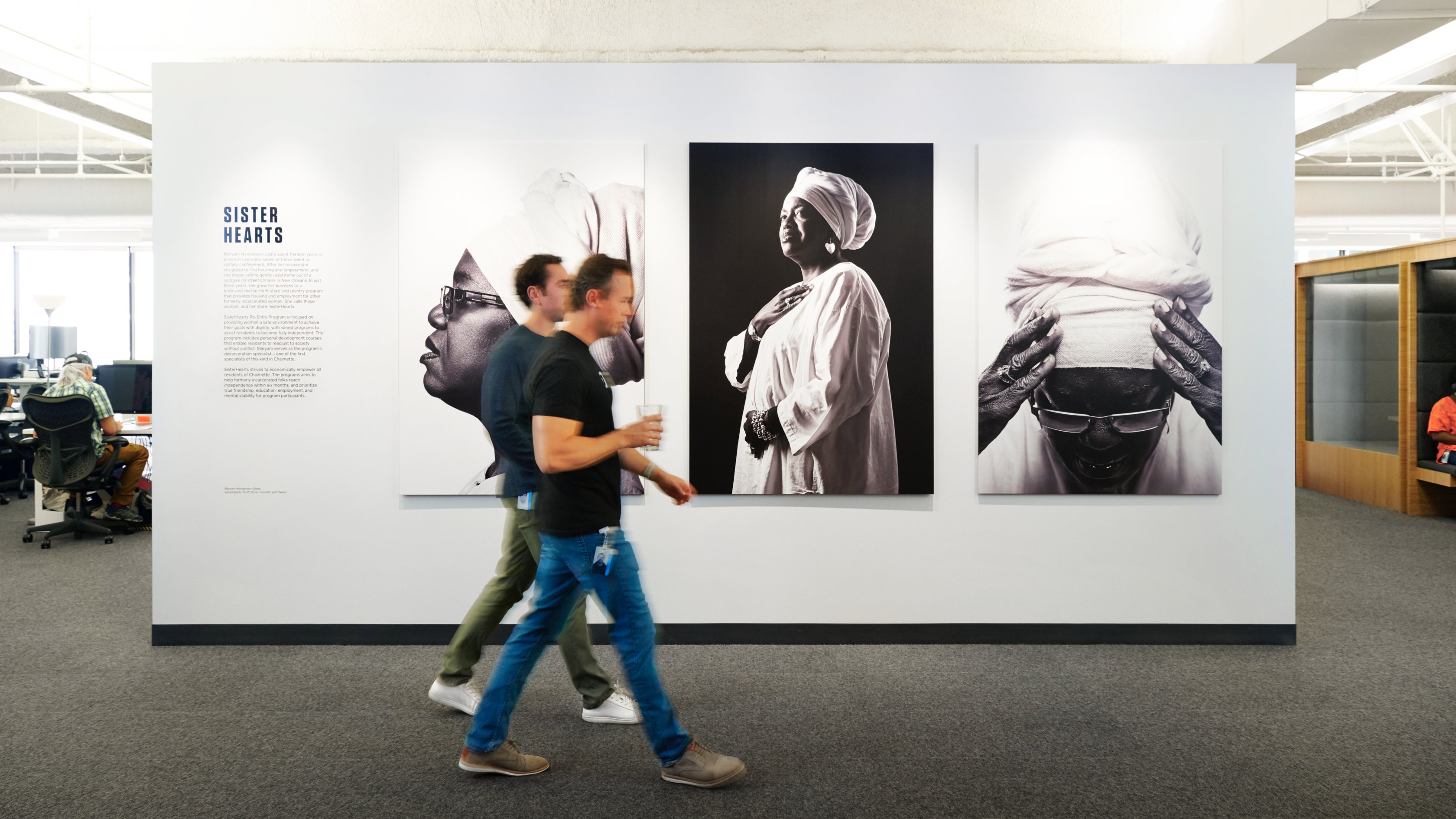 photo of two people walking past a wall with art