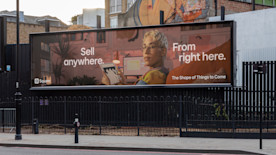 a photo of a billboard featuring a square ad with a person holding a tablet and the phrase: “Sell anywhere. From right here.”