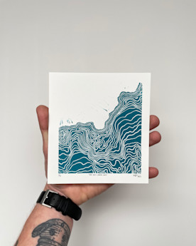 A hand holding a square-shaped blue and white print