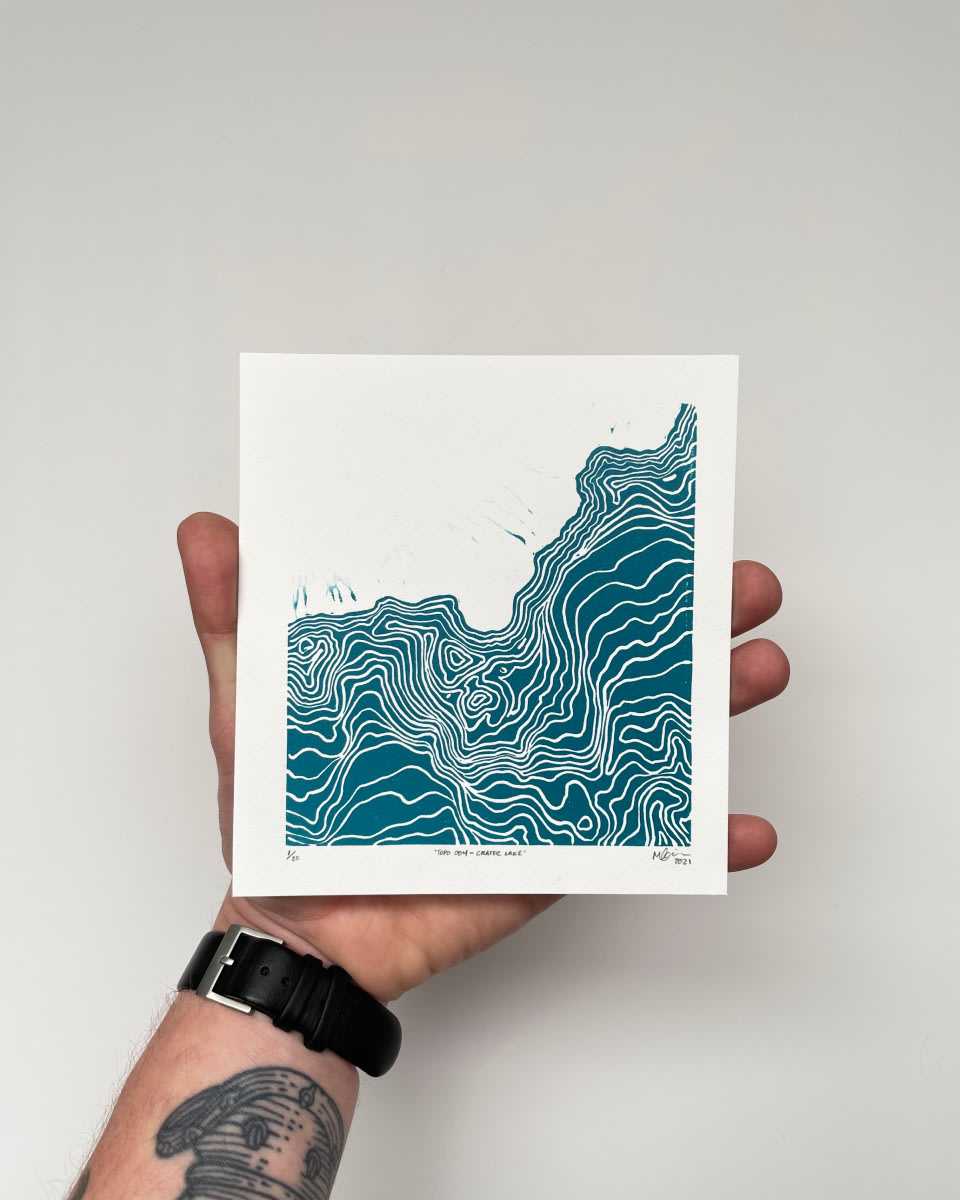 A hand holding a square-shaped blue and white print