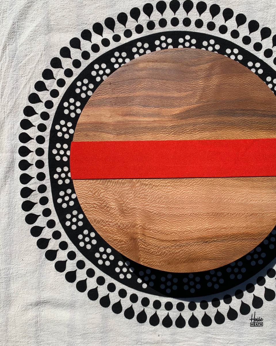 round wooden box, with intricate speckled grain, wrapped with a red elastic band, sitting on a decorative tablecloth