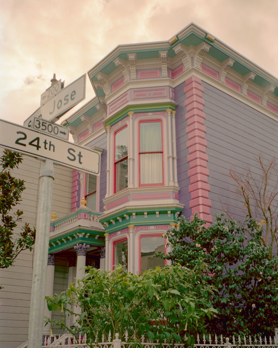 a photo of a colorful house with white street signs in the foreground