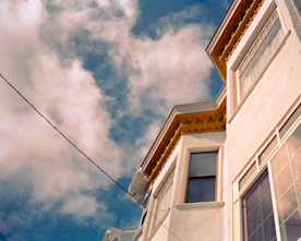 a photo taken looking up at a house against a blue sky with white clouds