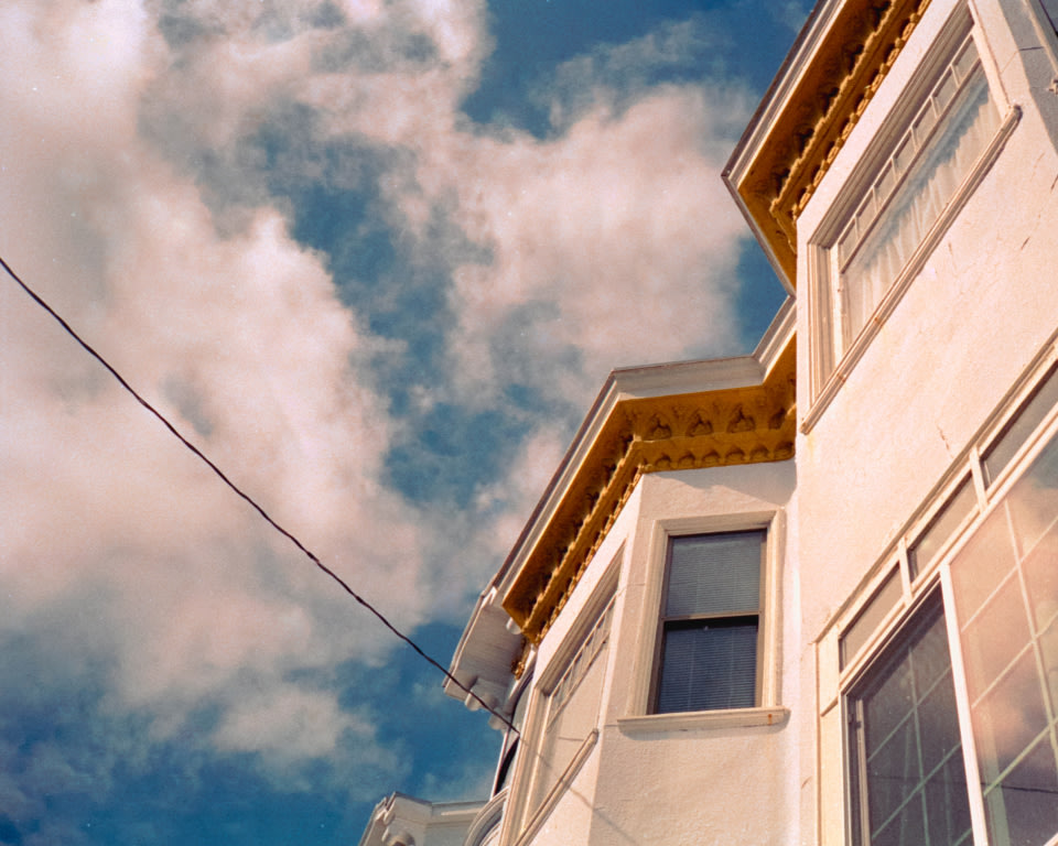 a photo taken looking up at a house against a blue sky with white clouds